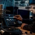 Hands adjusting microphone and audio interface in studio