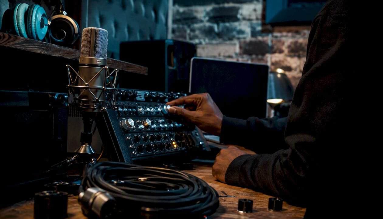 Hands adjusting microphone and audio interface in studio