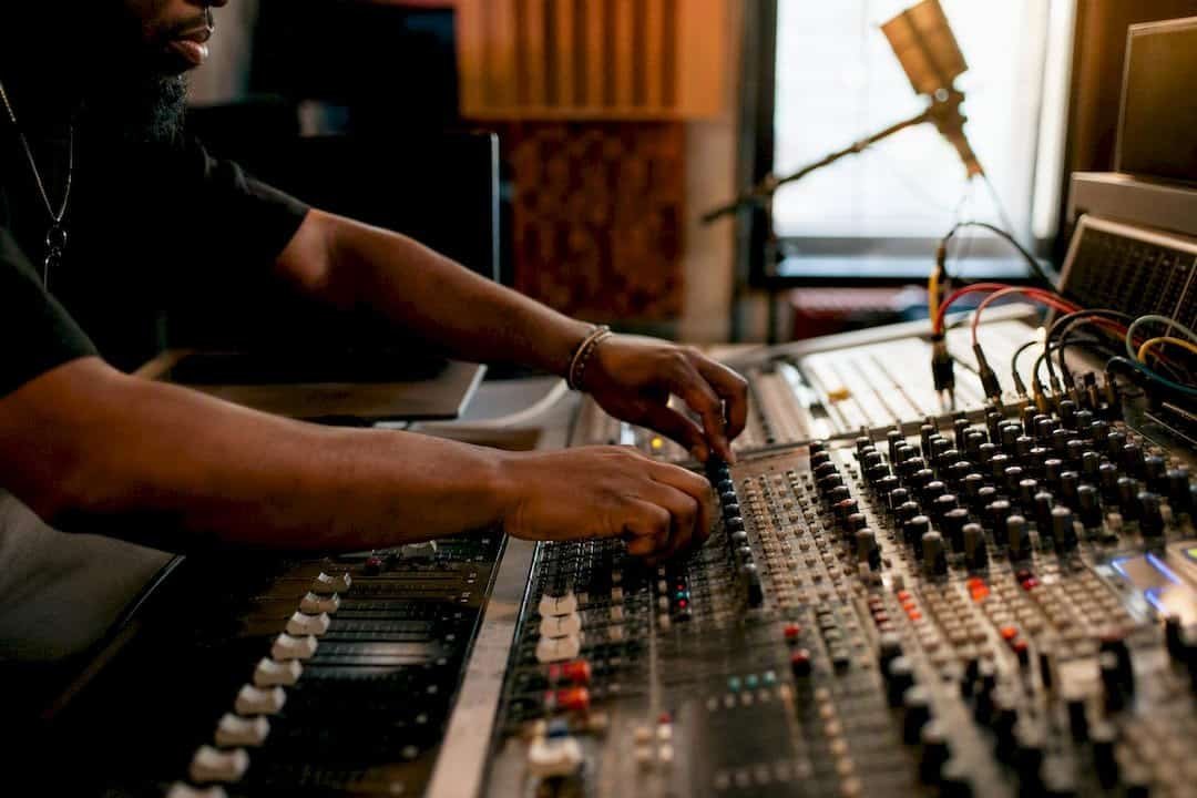 Hands adjusting mixing console controls