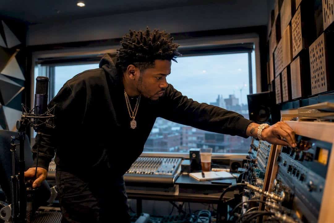 Hip hop artist adjusting DJ mixer in urban home studio